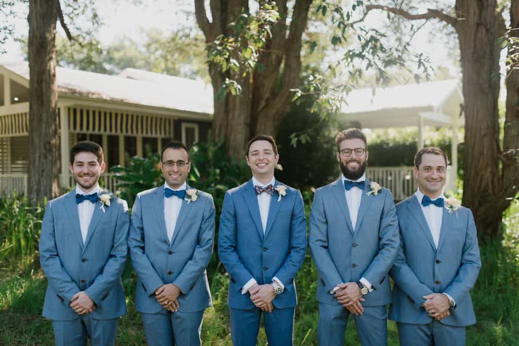 matching groomsmen in blue-grey suits with bow ties
