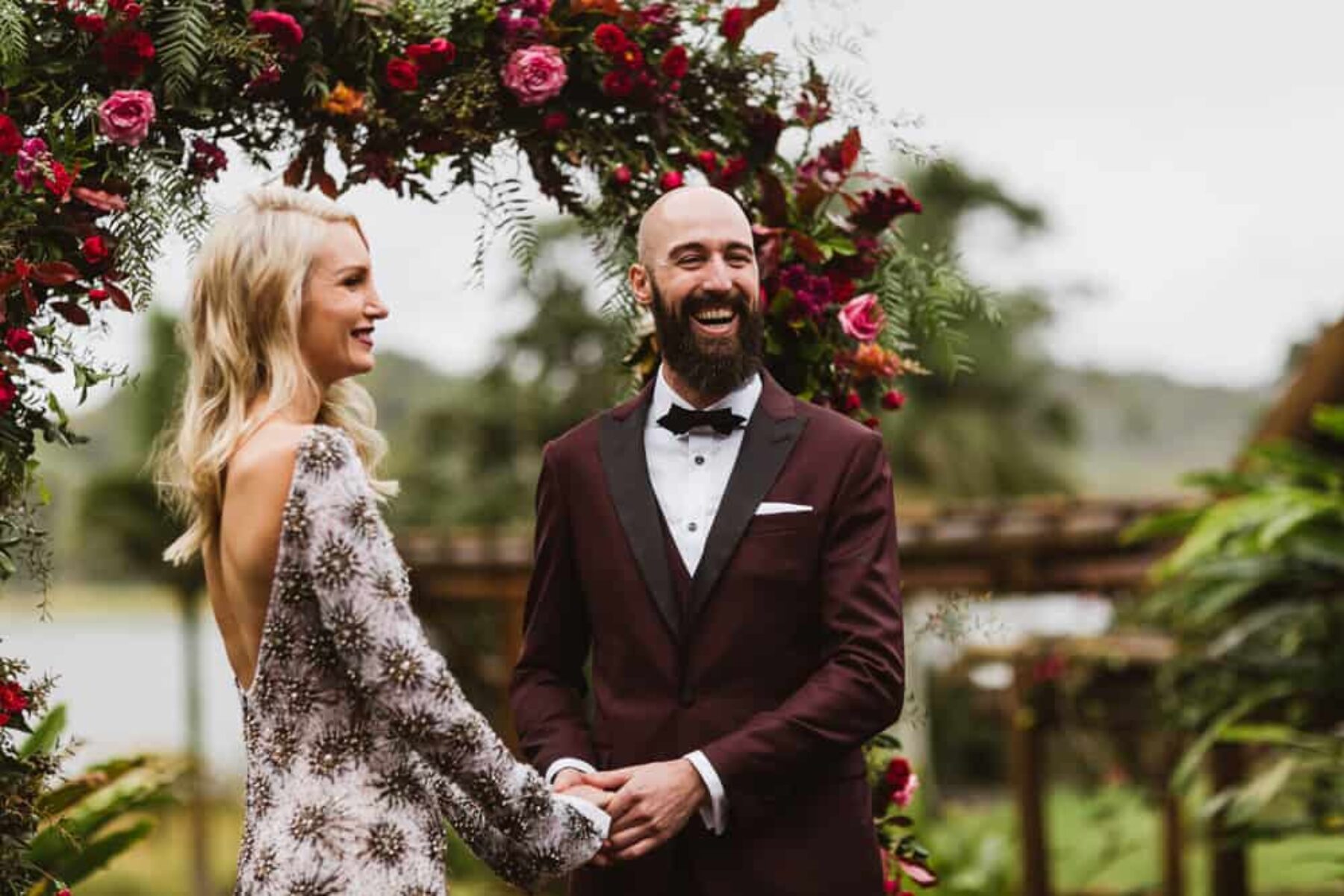 alternative bride in celestial sequin wedding dress and stylish groom in burgundy suit