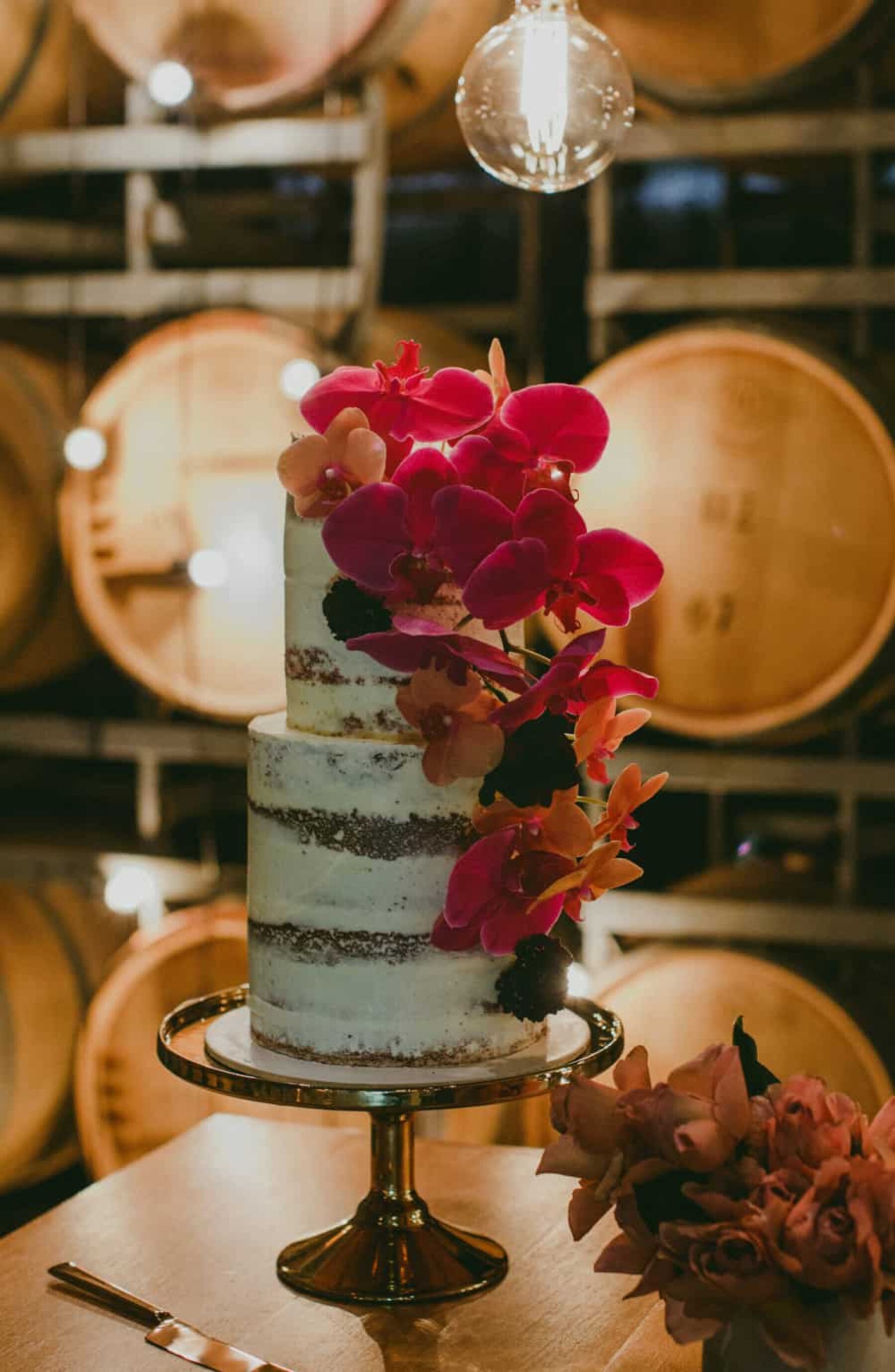 nearly naked wedding cake with pink orchids