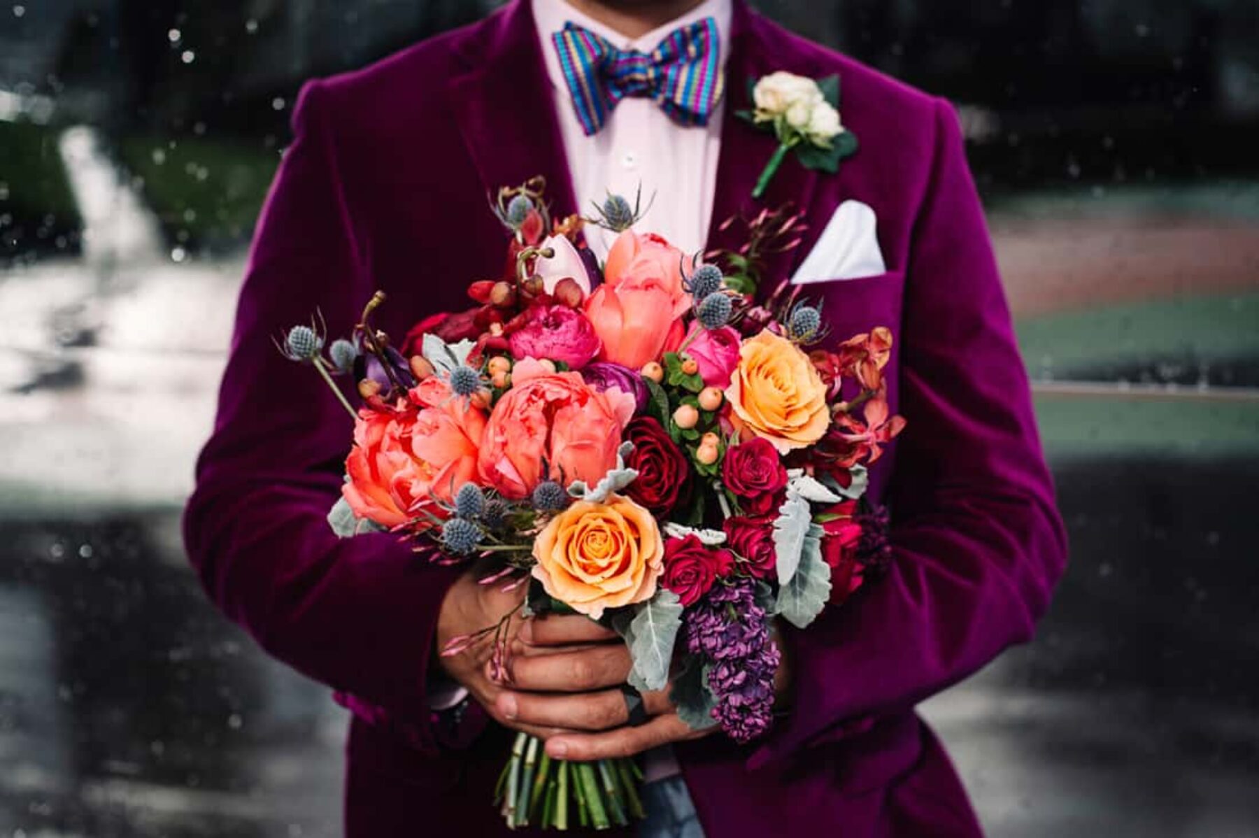 stylish groom in magenta velvet blazer with peach bouquet