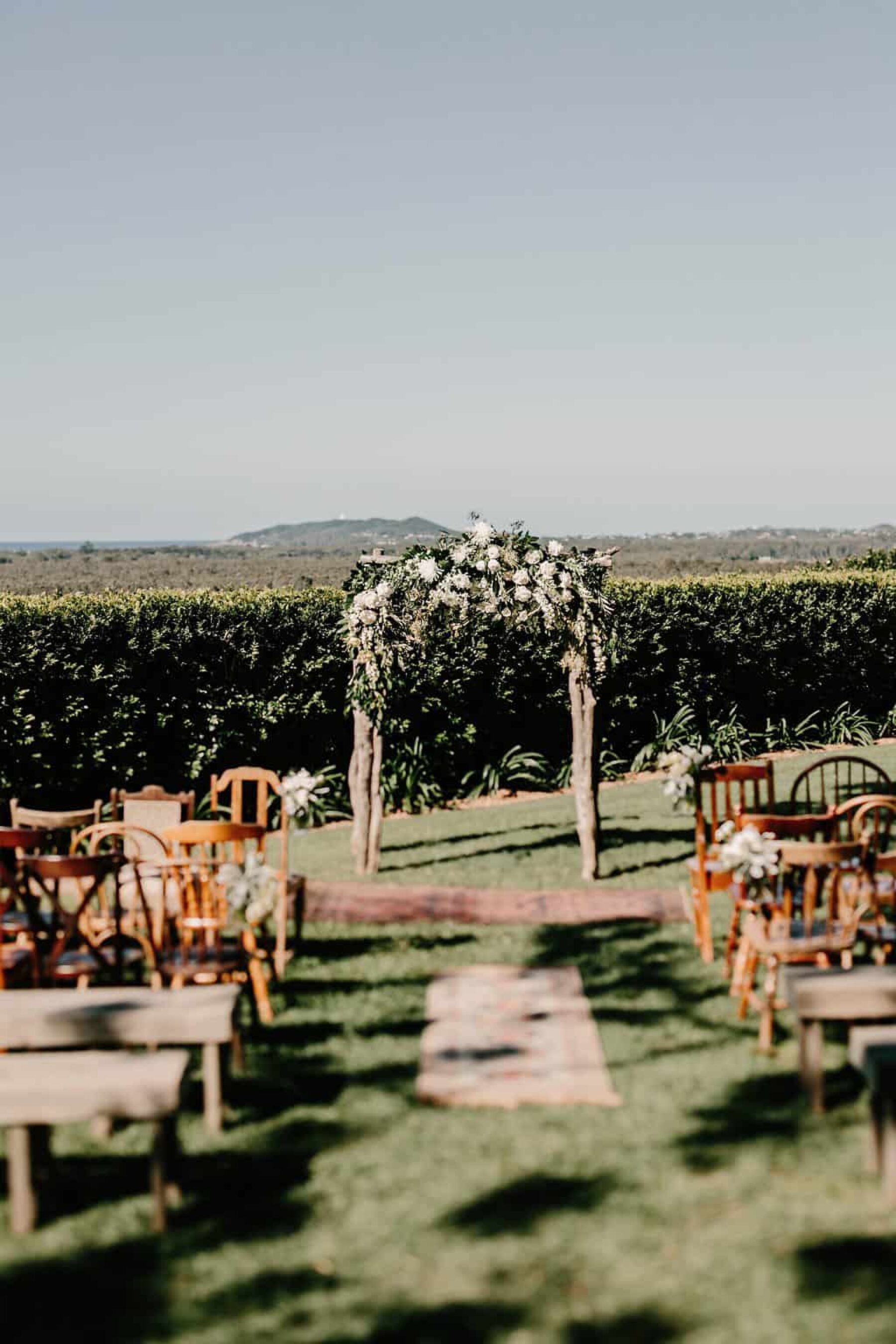 rustic floral wedding arbour with mismatched wooden chairs