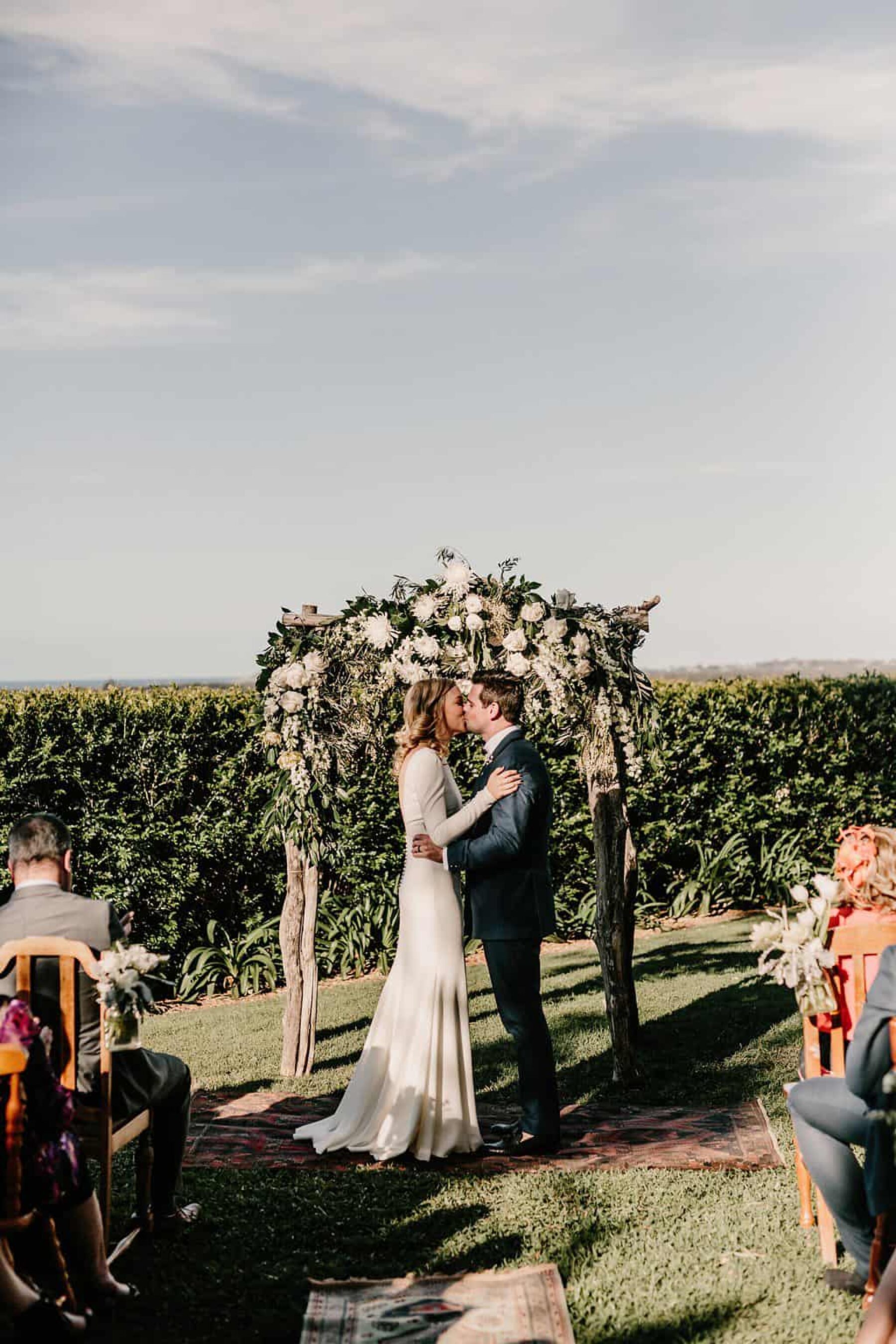 rustic floral wedding arbour with mismatched wooden chairs