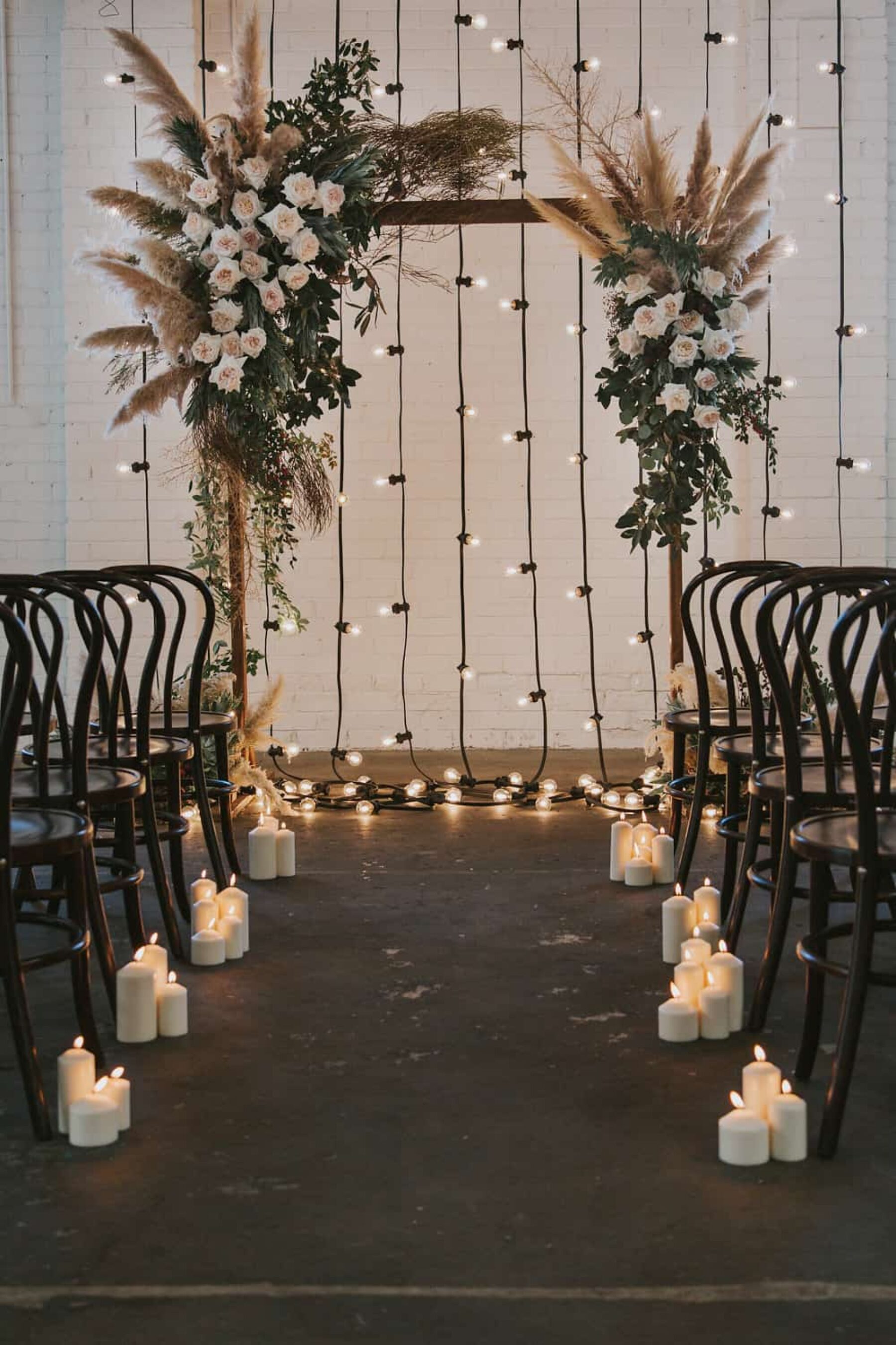 floral wedding arch with pampas plumes and festoon lights