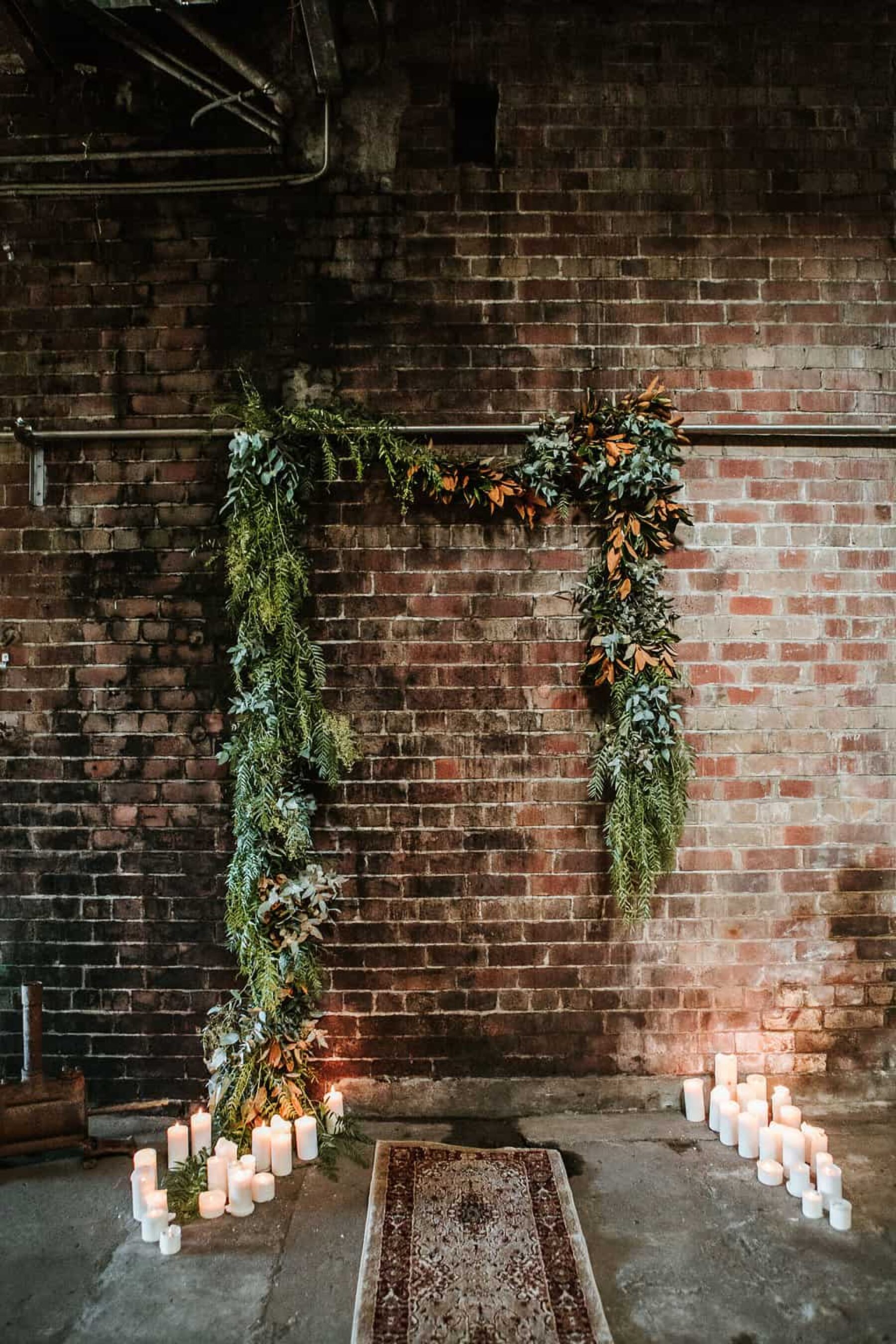 foliage garland wedding backdrop on exposed brick wall