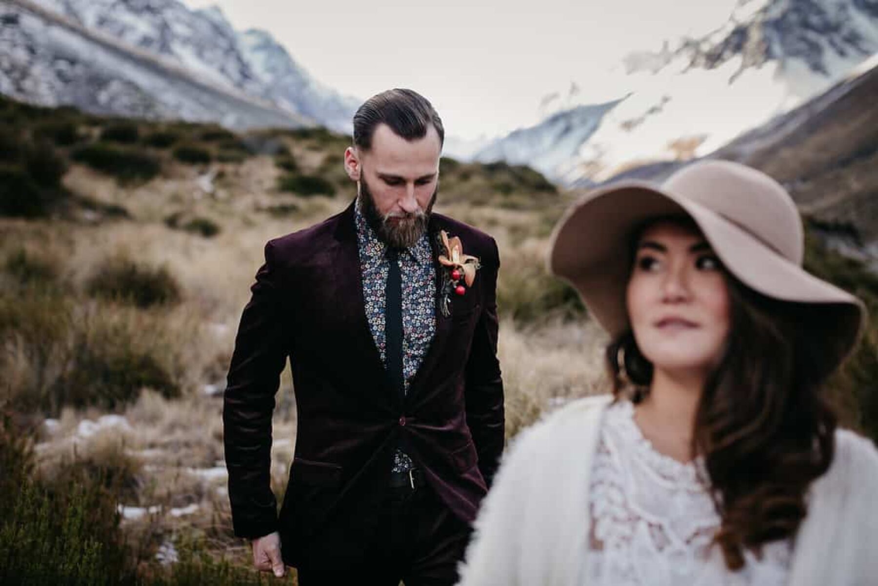 Boho bride and groom in burgundy suit with floral shirt