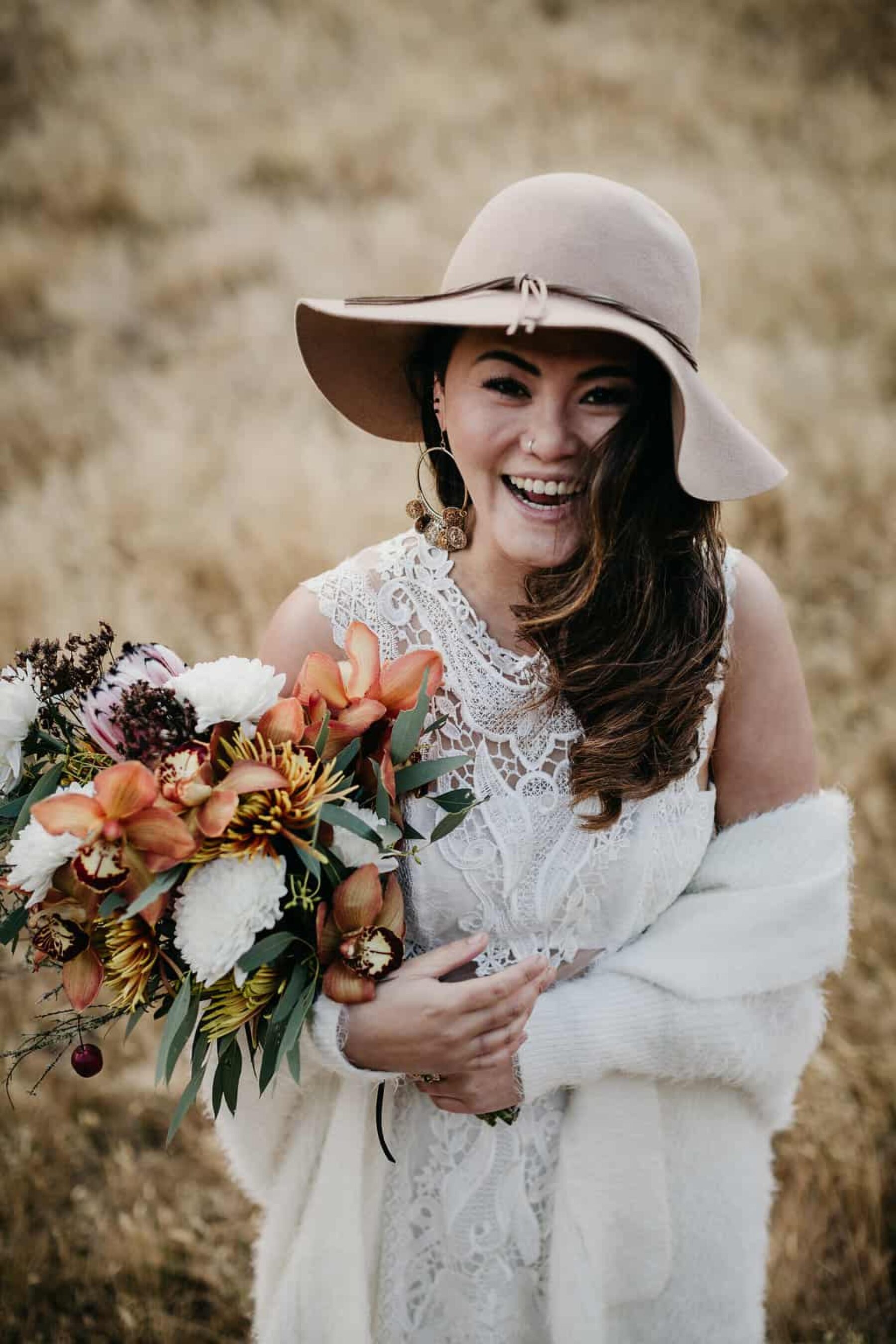 winter bride with wide brim hat and protea bouquet