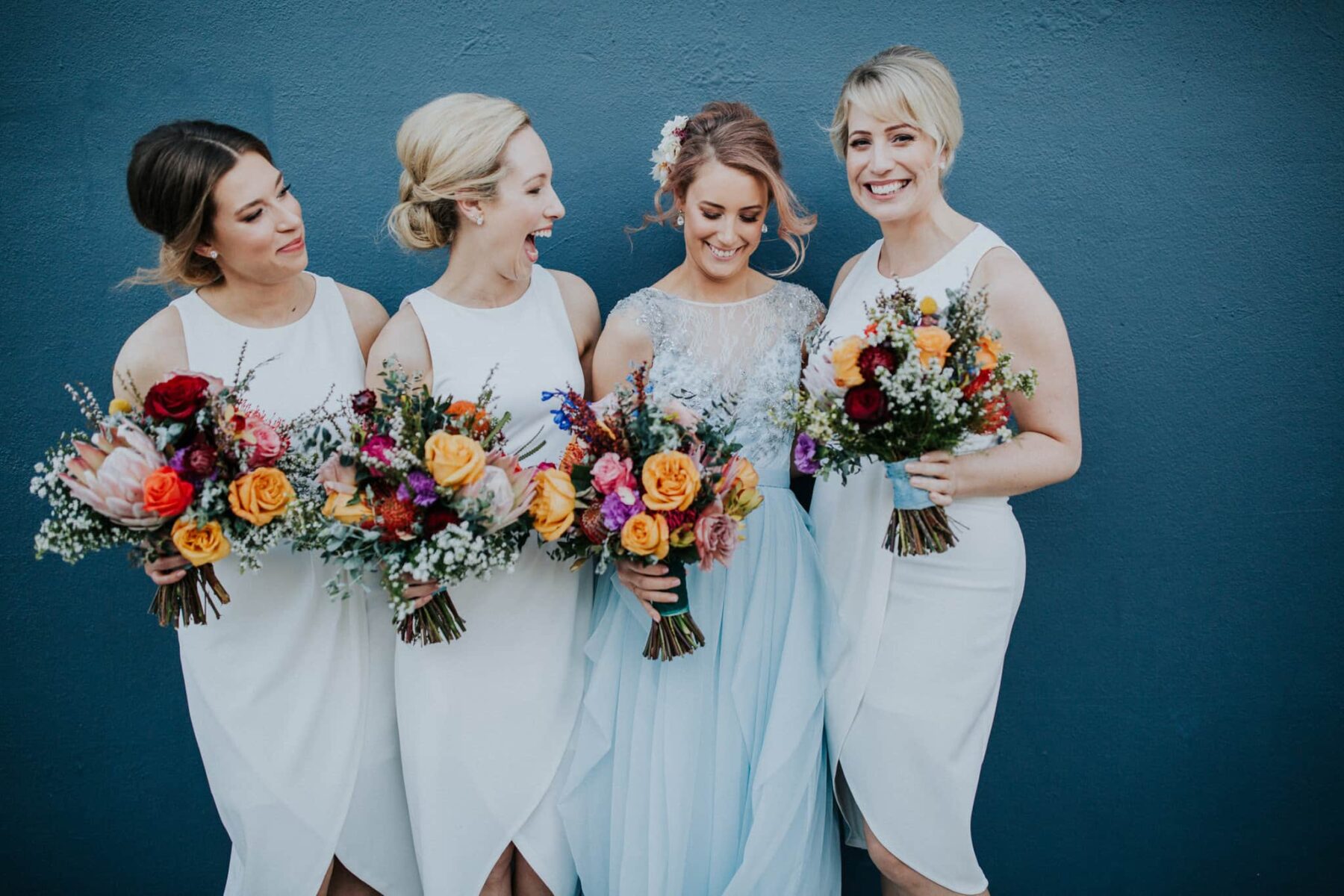 bridesmaids in modern white dresses with colourful bouquets