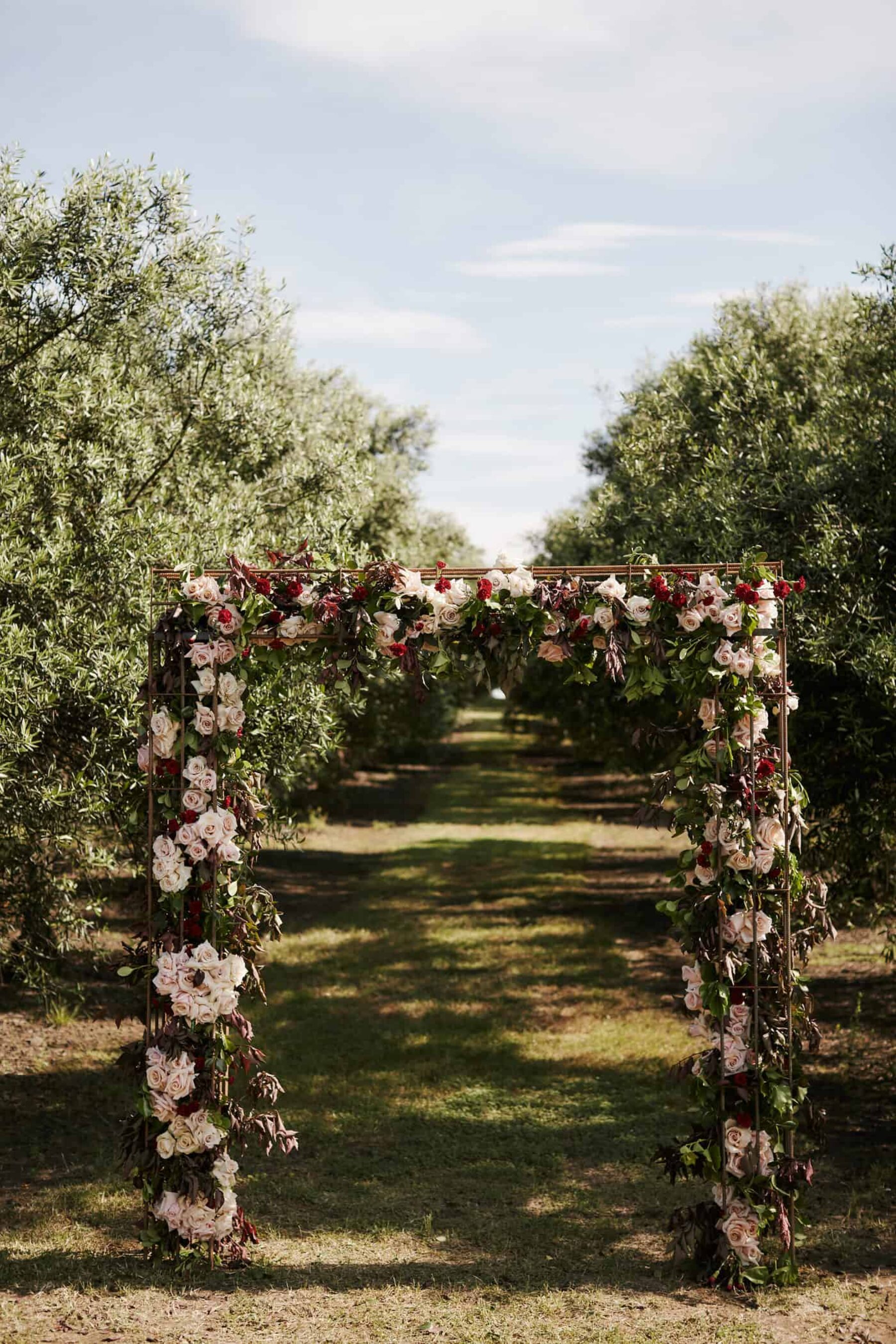 wire wedding arbour with blush and burgundy flowers