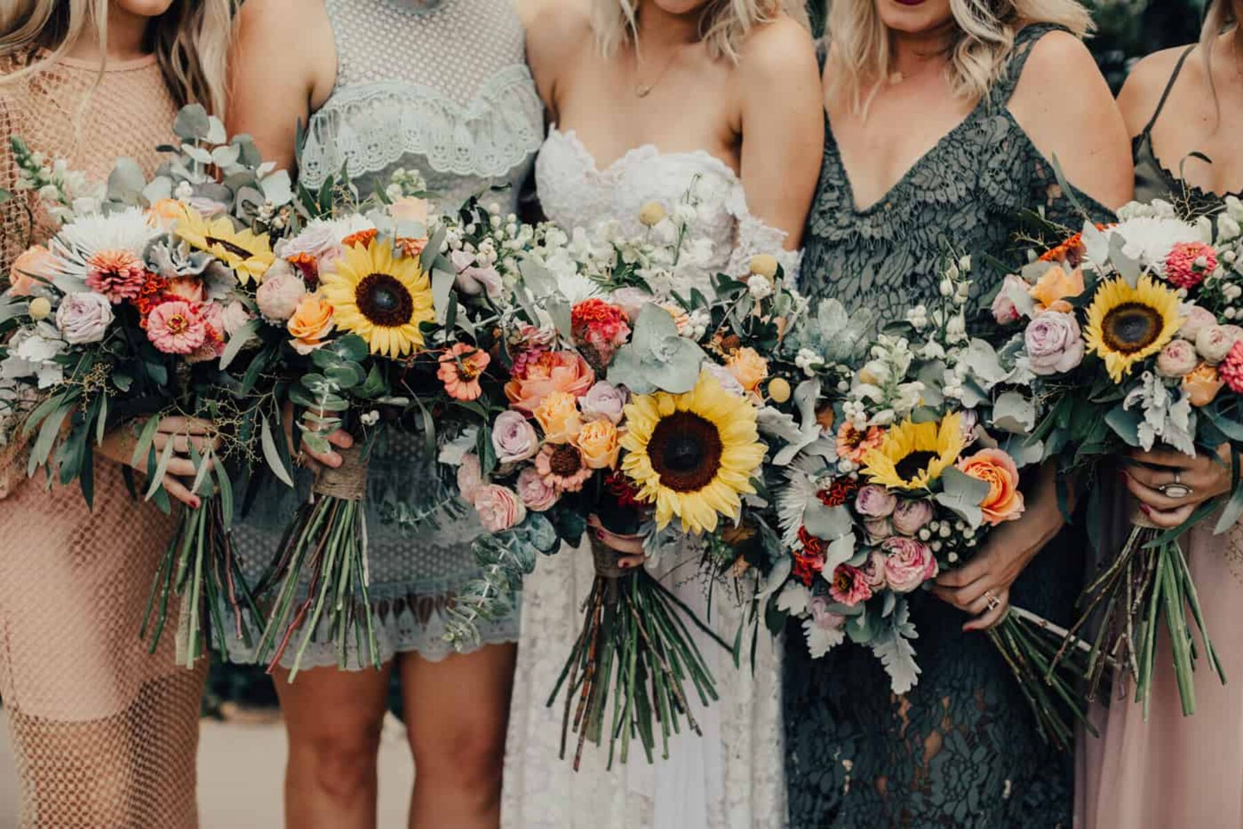 mismatched bridesmaid dresses in blush and sage with sunflower bouquets