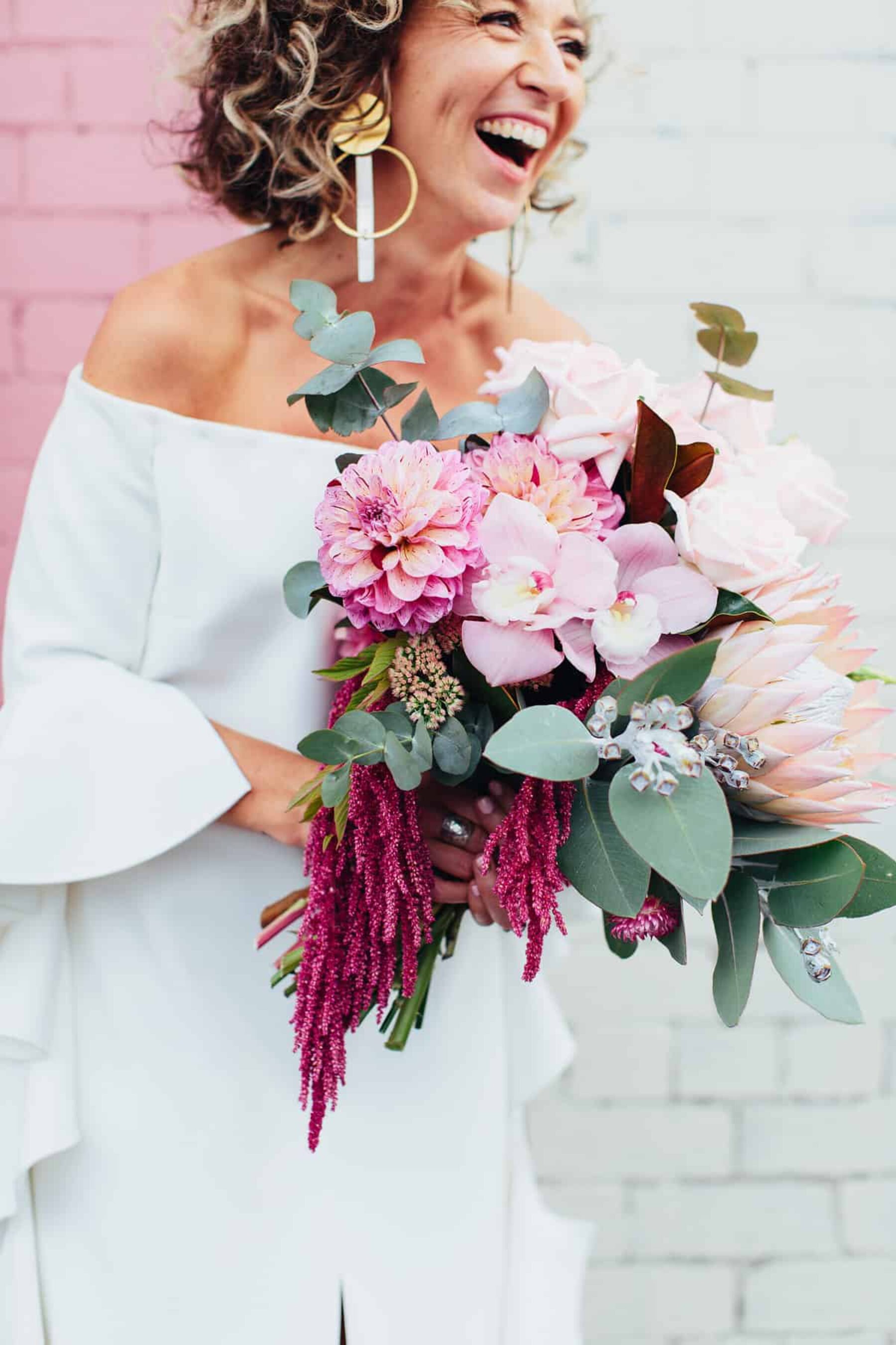 vibrant pink bouquet with with protea, amaranth and orchids