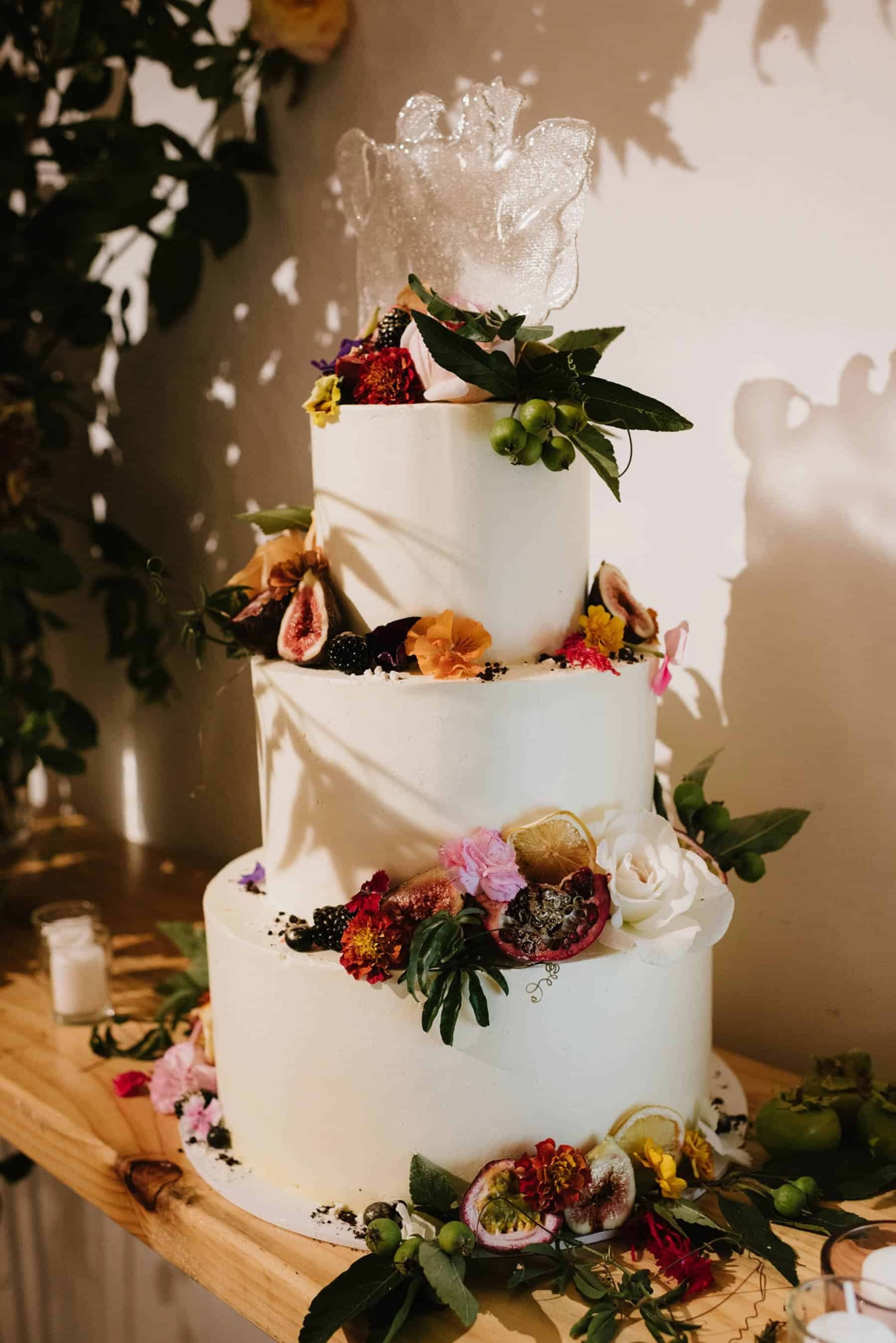three tier wedding cake topped with fresh flowers and fruit