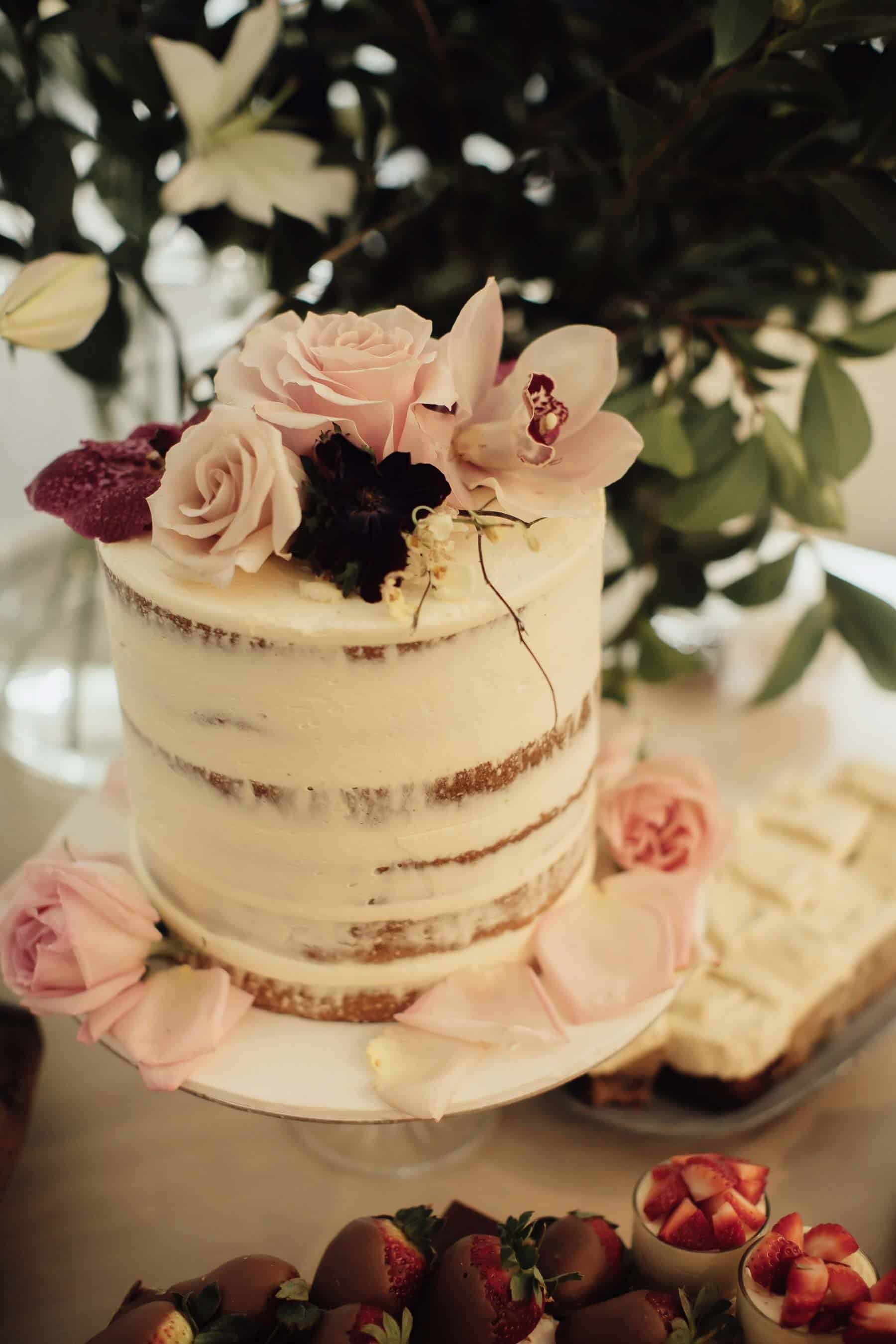 simple white wedding cake with blush flower topper