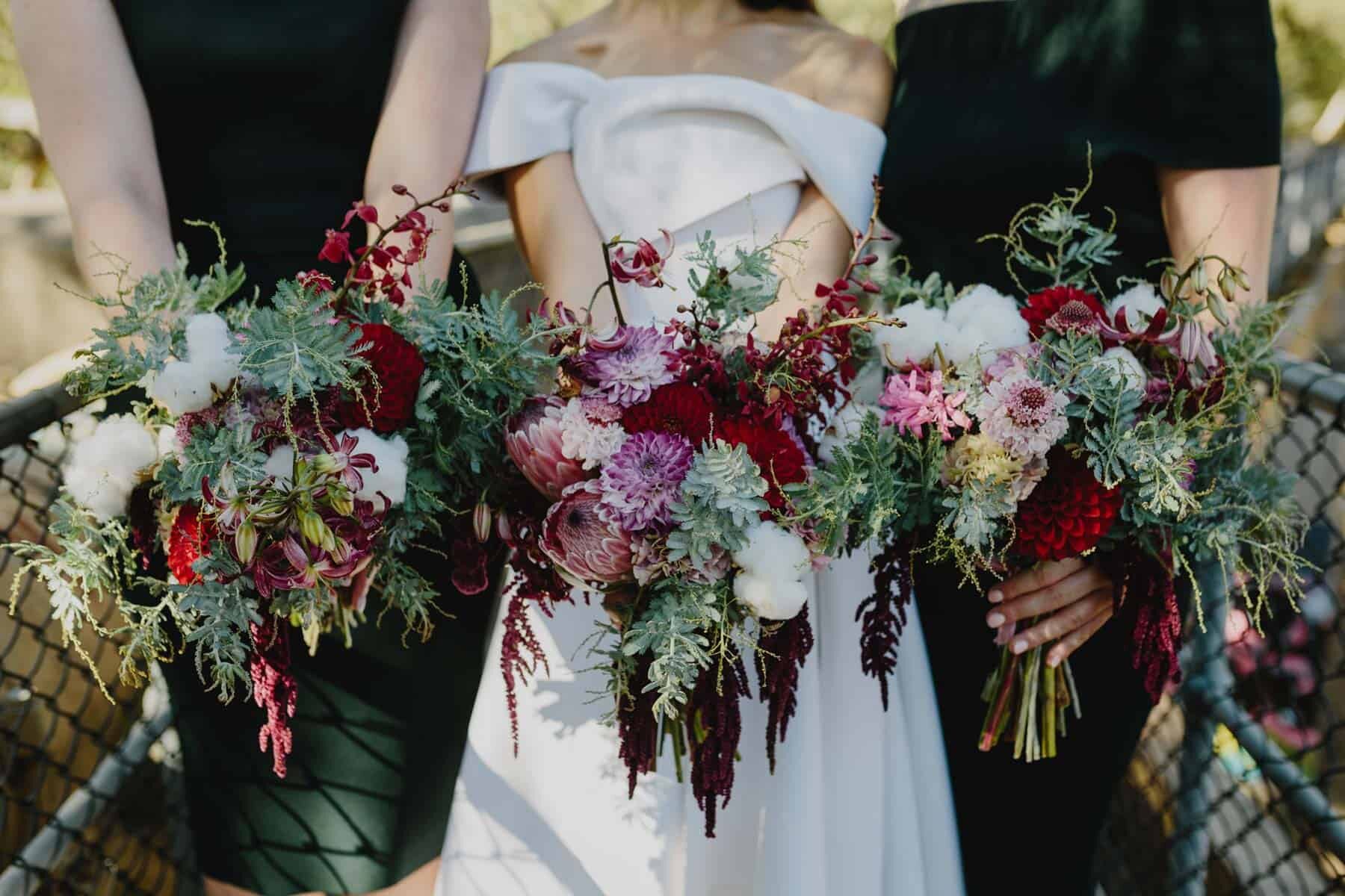 cascading berry-toned bridesmaids bouquets with proteas and amaranth
