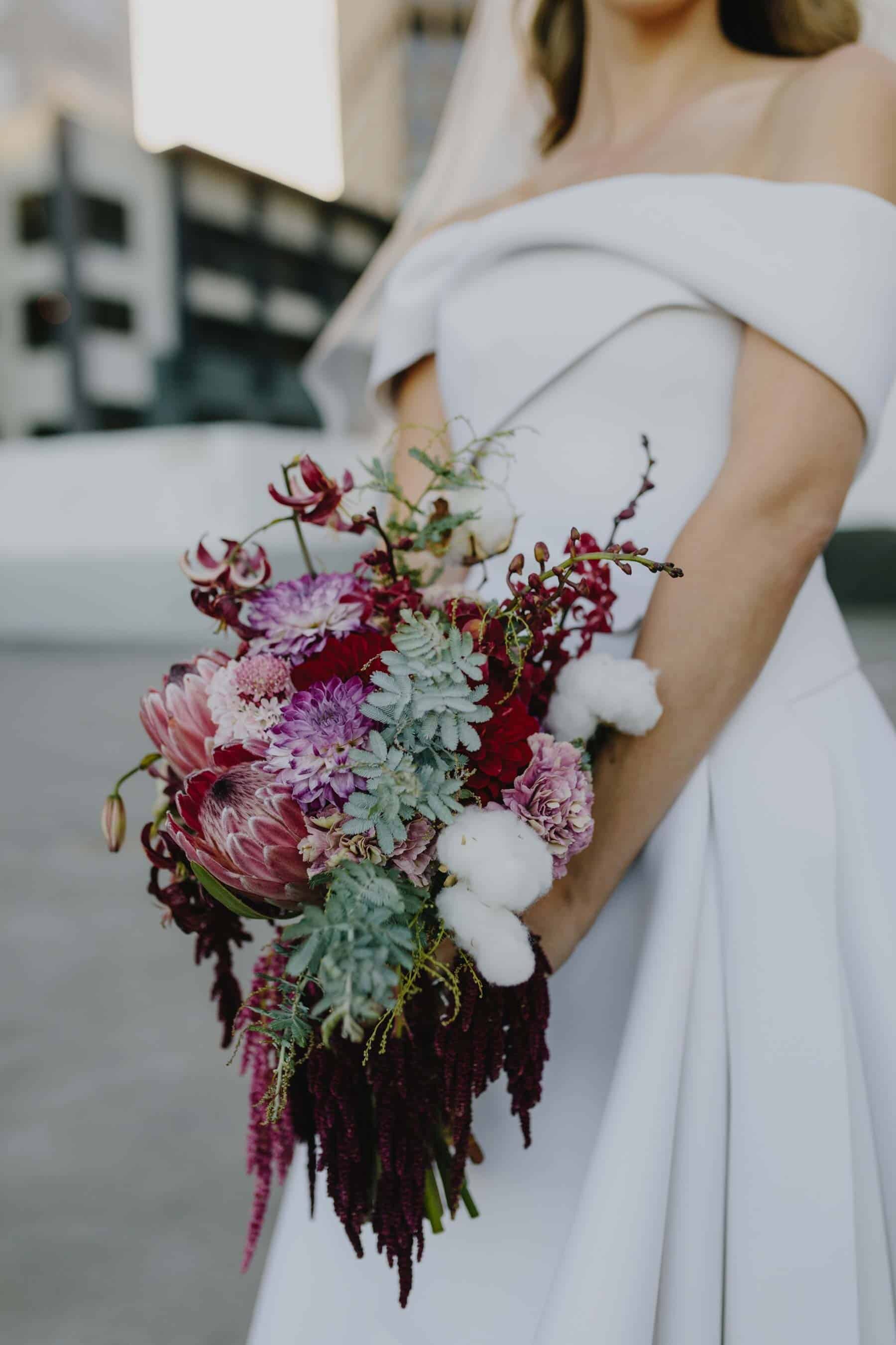 cascading berry-toned bridal bouquet with proteas and amaranth