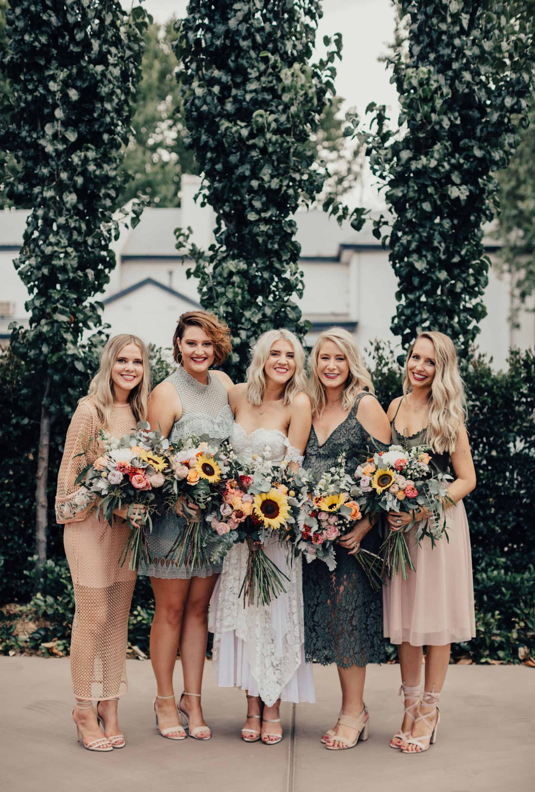mismatched bridesmaid dresses in blush and sage with sunflower bouquets