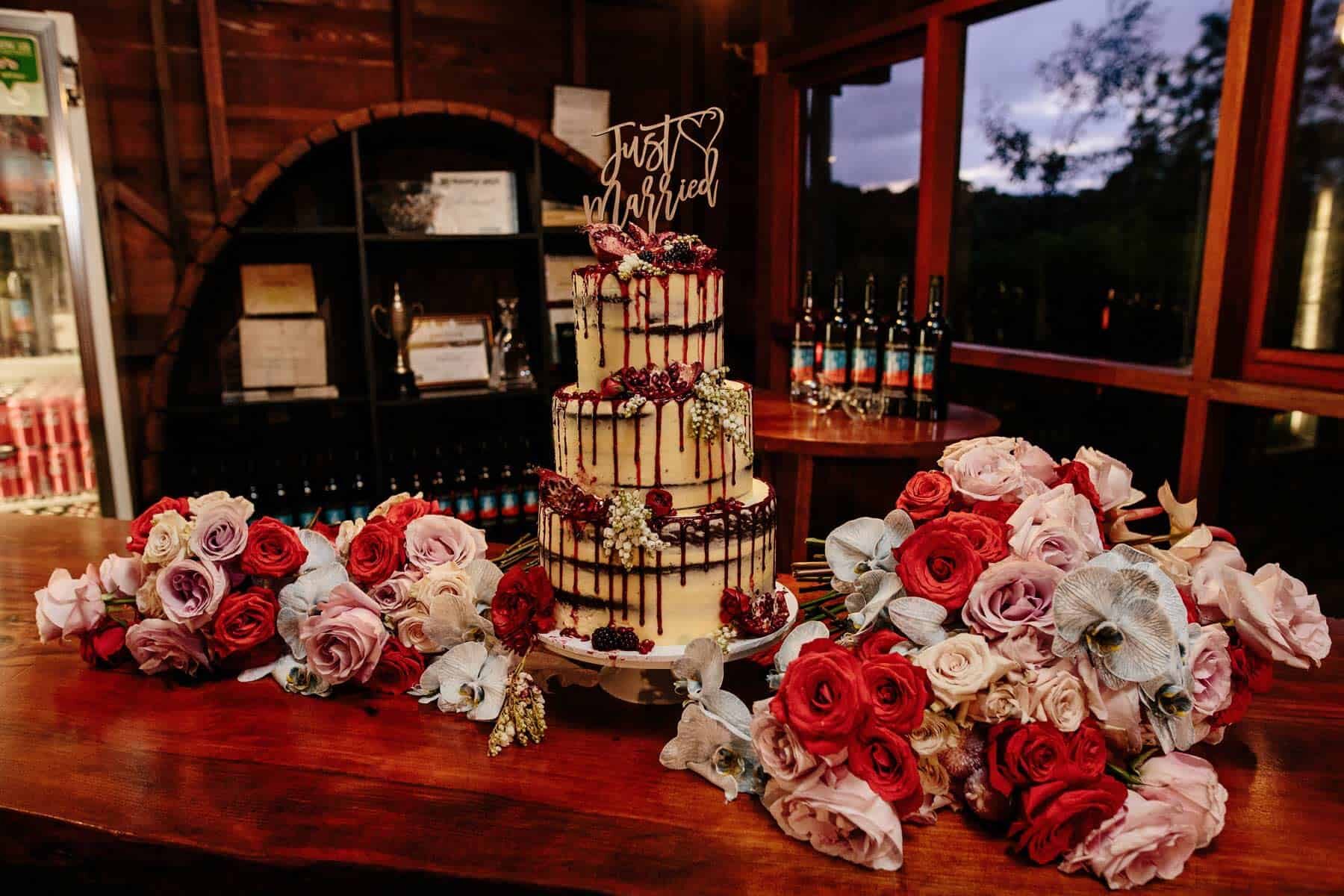 Three tier semi nude wedding cake with vibrant flower bouquets