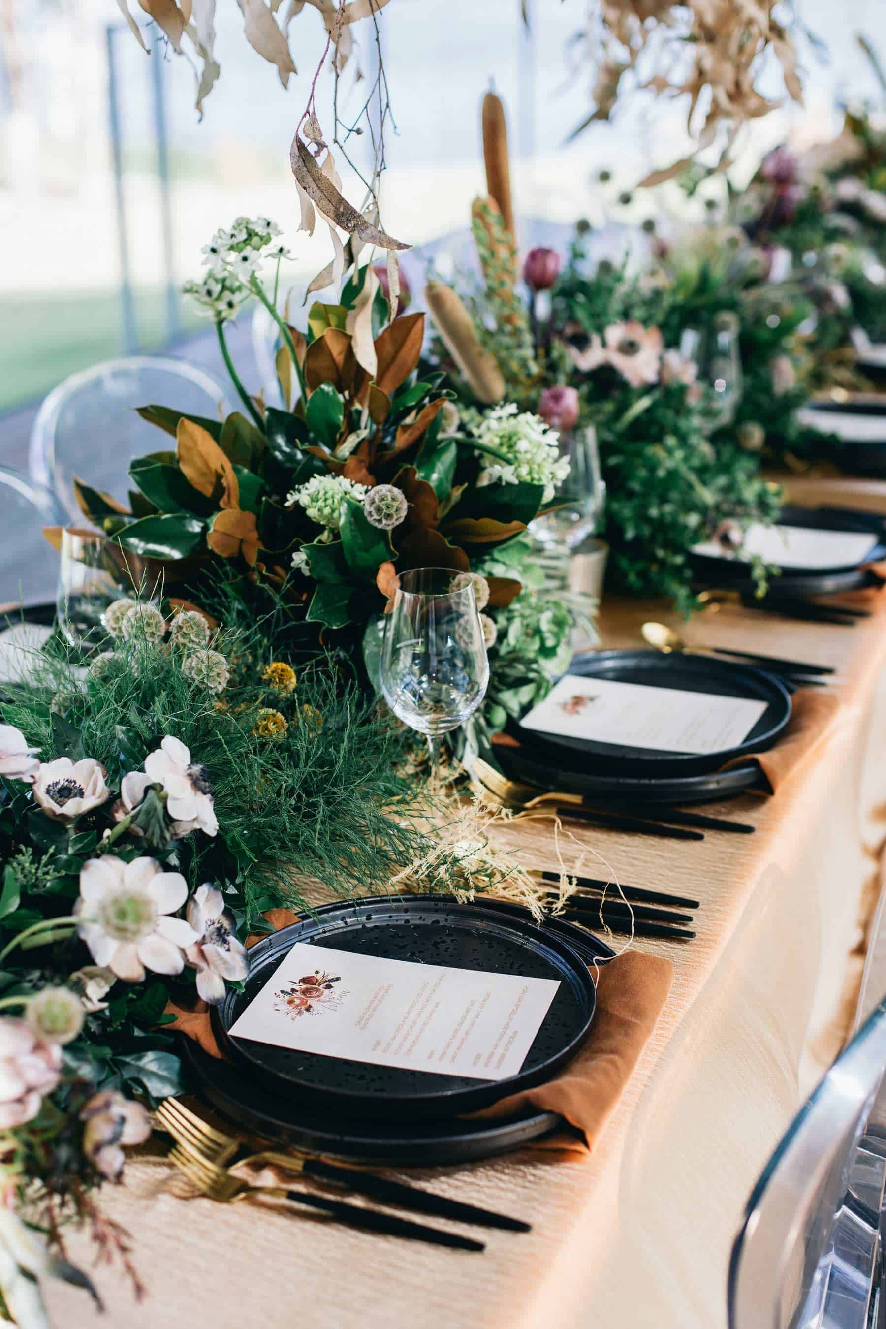 tablescape with black plates and gold cutlery