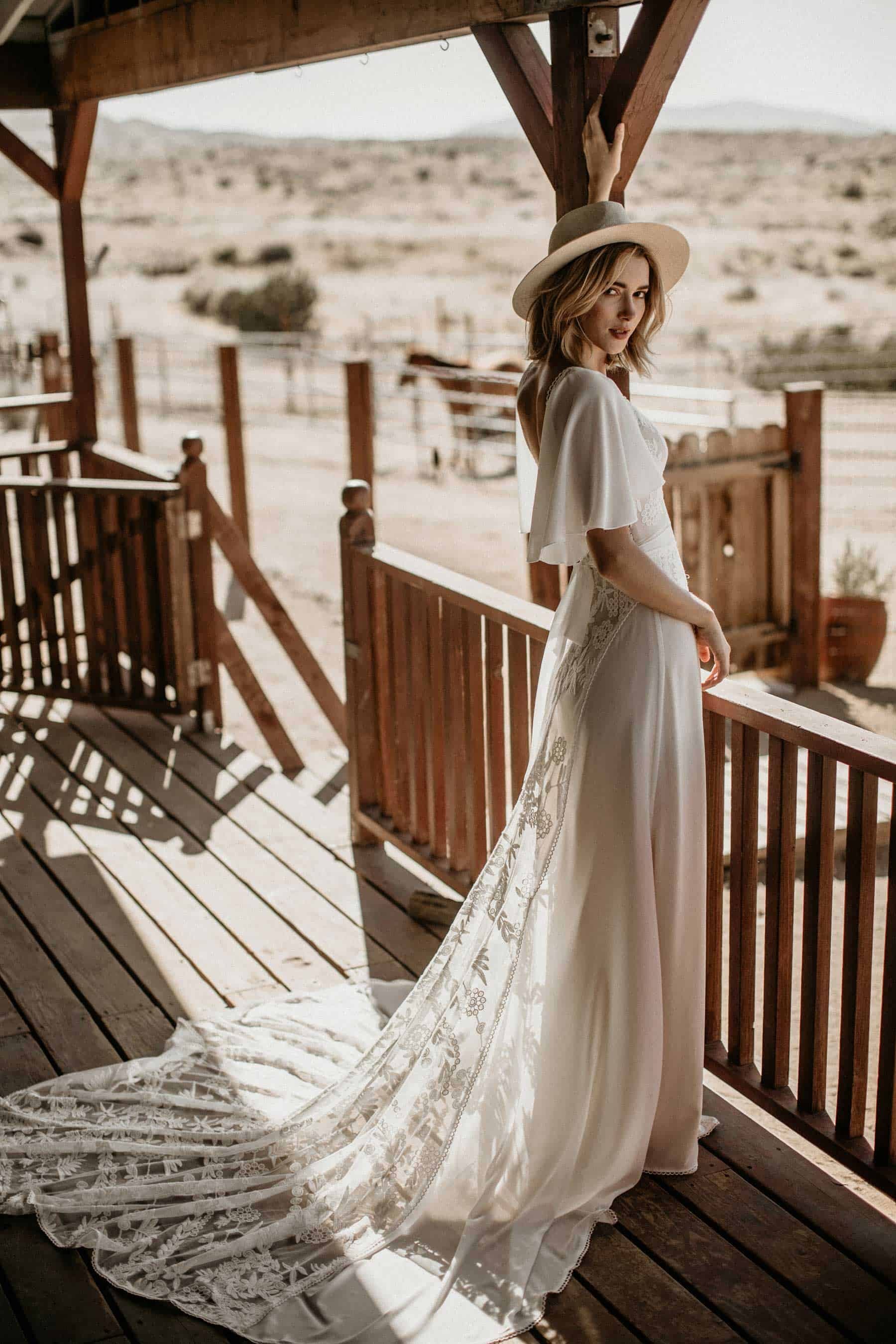 indie bride in cape-sleeve wedding dress and hat
